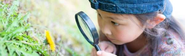 bug - Club SciKidz Greater Milwaukee girl with magnifying glass looking at flower